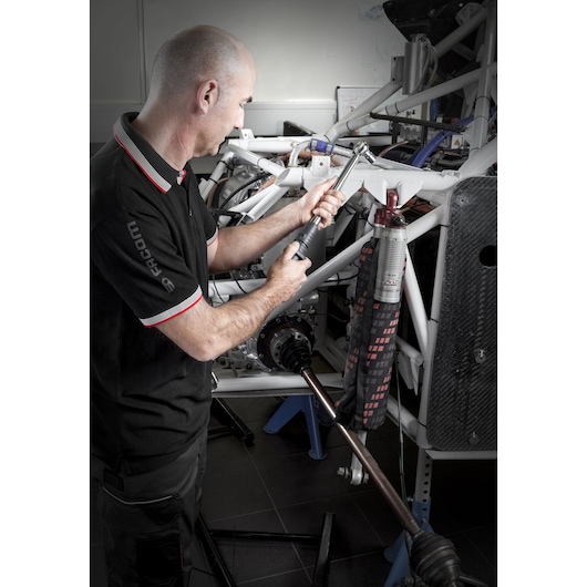 Facom S_209-340PB torque wrench in use by mechanic on automotive chassis, side angle, photography.