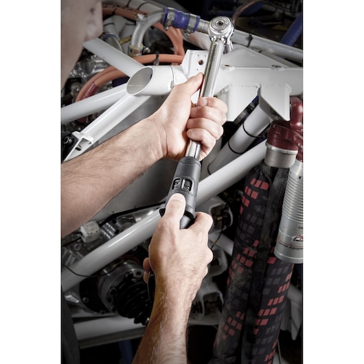 Facom S.209A340 torque wrench used by a person to tighten bolts on automotive machinery.