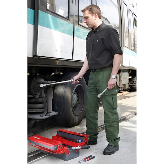 Facom S_306-100R red metal toolbox with tools next to technician working on train wheel.