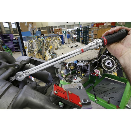 Facom S306A200 torque wrench with black handle in use tightening bolt on machinery in workshop.
