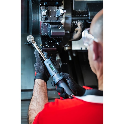 Facom S.307A340 digital torque wrench in use near machinery, close-up of gloved hands.