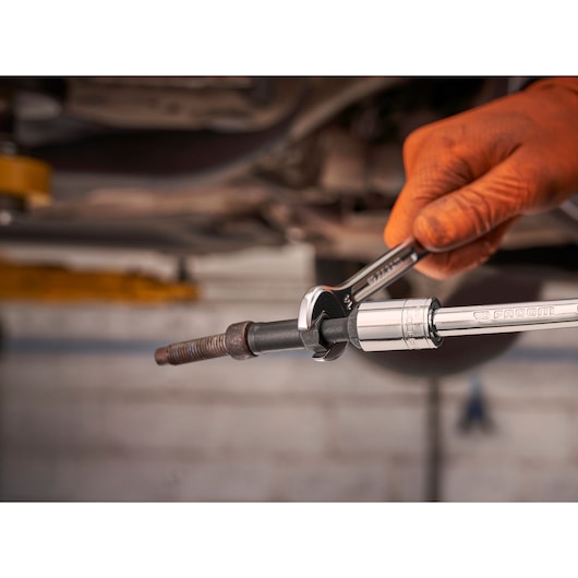 Facom SXE_J7MGRPPB spanner and socket wrench on rusted bolt, hand wearing orange glove.