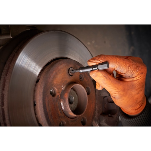 Facom SXE_J7MGRPPB hex bit used on vehicle brake disc by gloved hand, close-up photo.