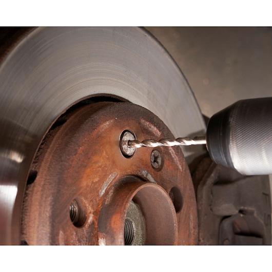 Facom SXE_J7MGRPPB close-up photography of drill bit drilling into rusty brake disc.