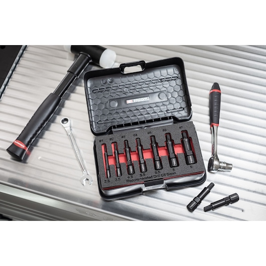Facom SXE_J7MGRPPB drill bit set in open black case, surrounded by hammer, wrench, and ratchet tools.
