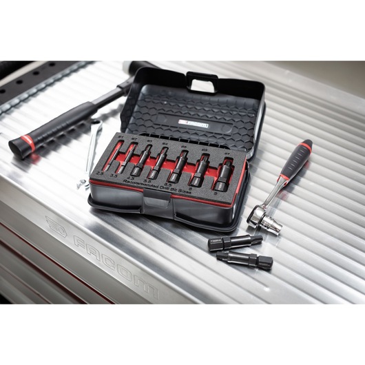 Facom SXE_J7MGRPPB extraction socket set in open black case on metal workbench, with ratchet and loose sockets.