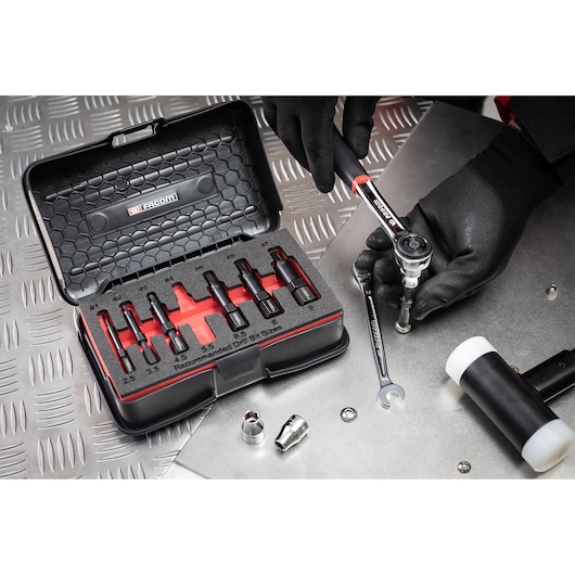 Photo of Facom hex bit socket set SXE_J7MGRPPB with open black case, assorted bits, and hand using ratchet wrench.