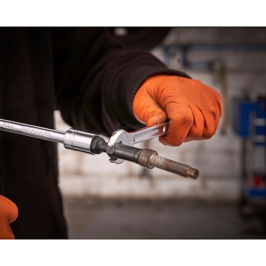 Photo of Facom wrench and socket tool SXE_J7MGRPPB used on a bolt, person wearing orange gloves.