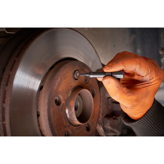 Facom SXE_J7MGRPPB hand tool used on car brake disc by gloved hand, close-up photo.