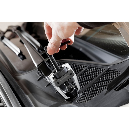 Facom U_14A wiper arm puller tool in use on a car windshield wiper arm, close-up photo.