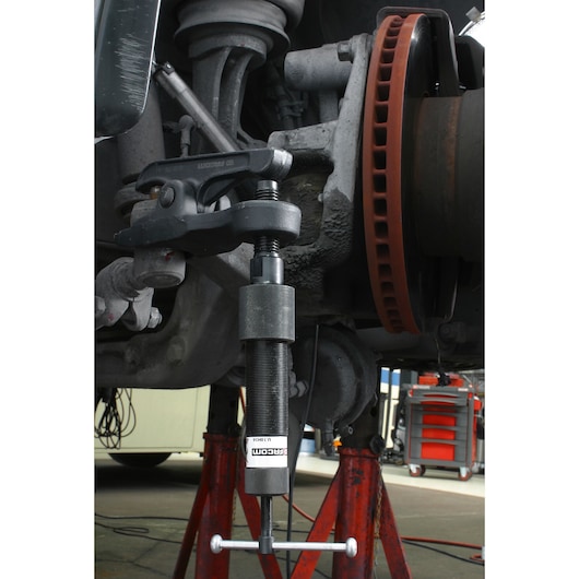 Facom U_18H36 automotive puller tool in use on a suspension component, close-up angle.