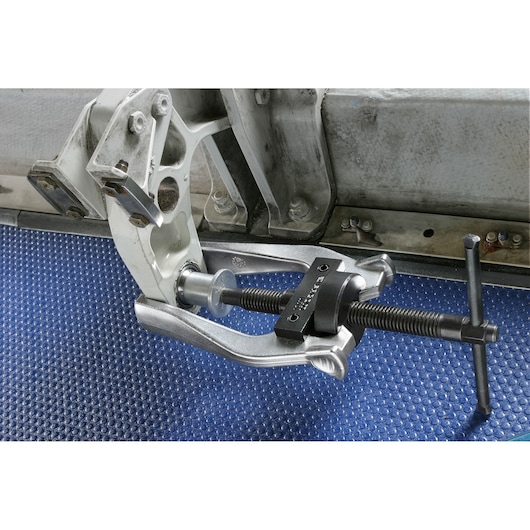 Facom U_301P bearing puller tool mounted on metal automotive part, shown in workshop setting.