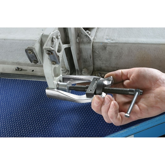 Facom U_301P bearing puller tool in use on mechanical part, close-up of hand operating tool.