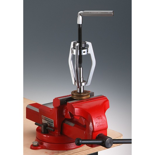 Facom U_302 gear puller tool in use, mounted on red bench vise, front angle on white background.