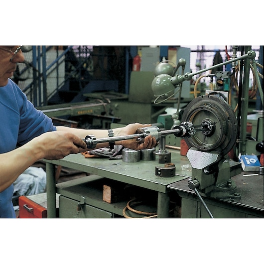 Facom U_306M bearing puller in use on a workshop bench with mechanical parts and tools.