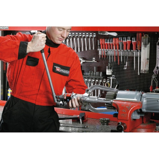 Facom U312H photography showing a technician in red coveralls using a tool in a workshop with organized hand tools.