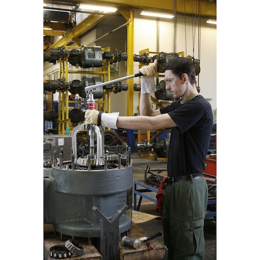 Photo of Facom U312H puller in use by worker in industrial workshop extracting bearing from machinery.