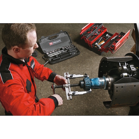 Facom tool set SKU U_32T2-12 in use for automotive repair, with mechanic and open toolboxes visible.