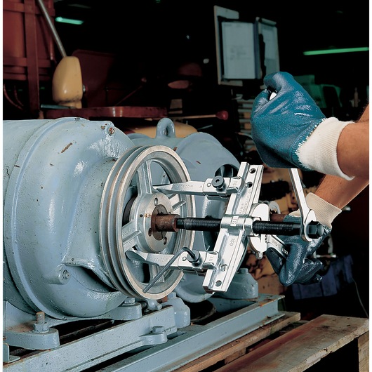 Photo of Facom puller tool U_32T6-20 in use on industrial machinery, mechanic with blue gloves operating the tool.
