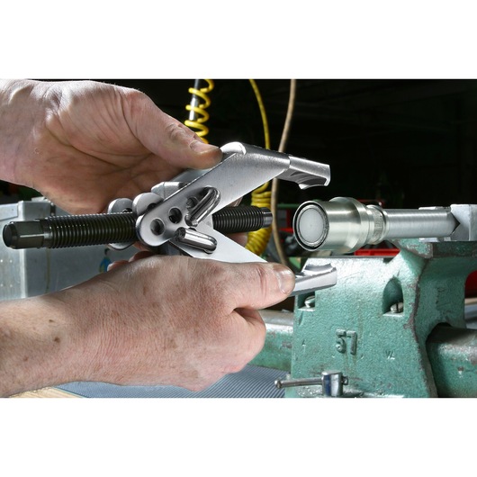 Facom U_35P bearing puller tool in use, close-up of hands operating on a metal shaft in workshop setting.