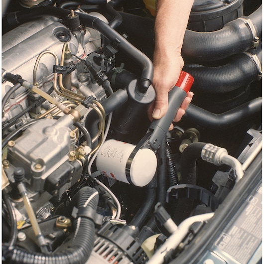 Facom U_46ACL oil filter wrench being used in a car engine bay, hand gripping tool.