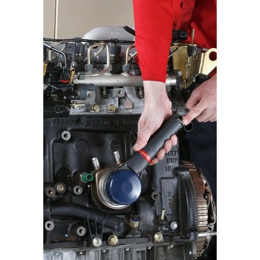 Facom U_48PL photography of oil filter wrench in use on engine, close-up view.