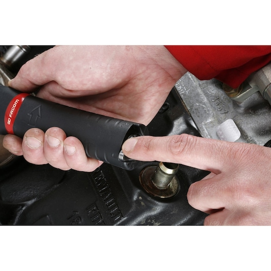 Photo of Facom U_48PL hand tool being used on an engine part, close-up view showing hand positioning.