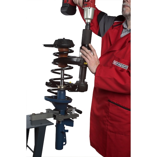 Facom U_89JMA photography of technician using tool on car suspension spring, white background.