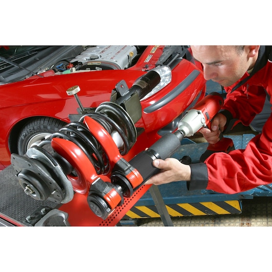 Facom U_89M230 photography of mechanic using red spring compressor tool on car suspension.