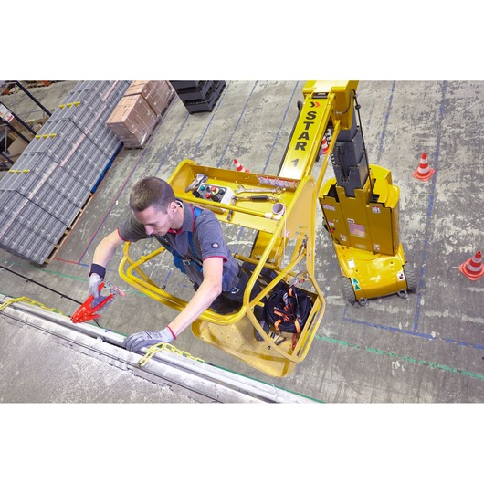 Facom WRT-DSLS tool set in use on aerial work platform, worker using pliers at height, warehouse setting, top-down view.