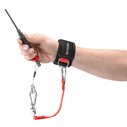 Facom WRT-DSLS wrist strap with red safety tether, attached to a screwdriver, shown on a person's wrist, white background.